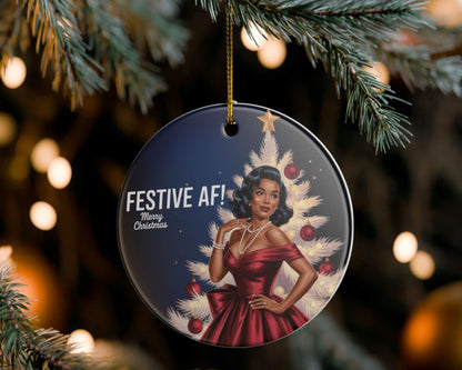 Decorative Christmas ornament with a woman in a red dress and festive tree design, hanging on a tree.