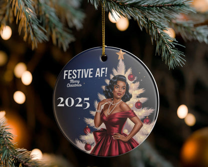 Decorative Christmas ornament with a woman in a red dress and festive text, hanging on a tree.