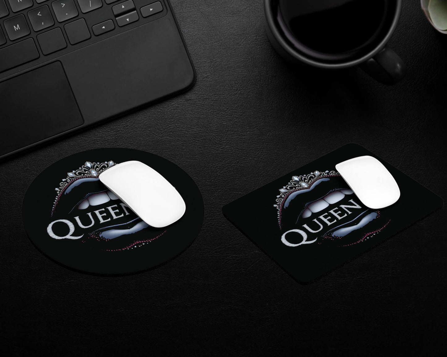 Two mouse pads with 'Queen' logo on a dark surface next to a keyboard and mug.