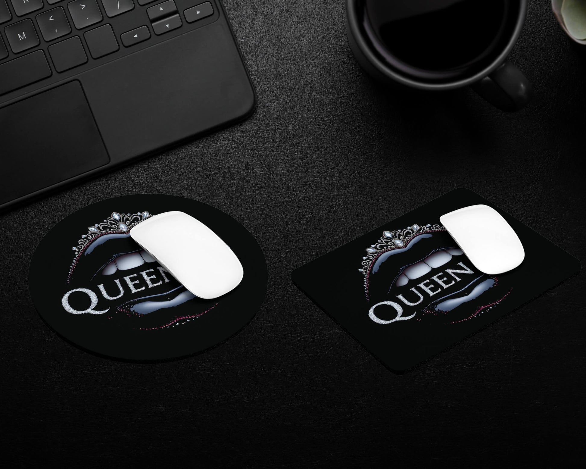 Two mouse pads with 'Queen' logo on a dark surface next to a keyboard and mug.