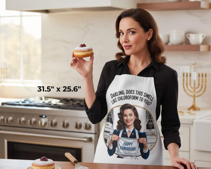 Woman in a kitchen wearing a Hanukkah-themed apron, holding a donut.