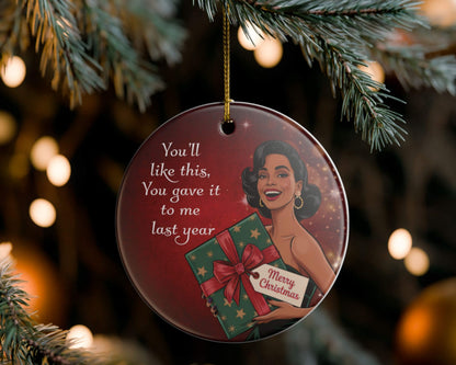 Decorative Christmas ornament with a woman holding a gift and text, hanging on a tree.