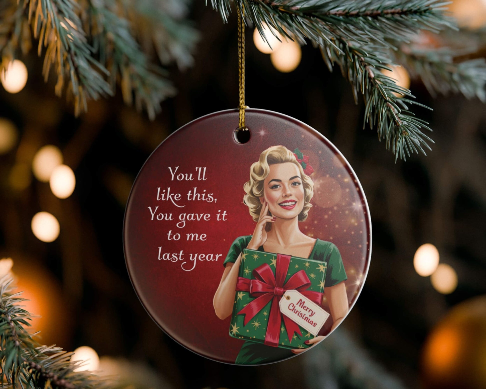 Christmas ornament with a woman holding a gift and text, hanging on a tree.