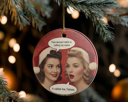 Christmas ornament with two women in Santa hats and humorous text, hanging on a tree.