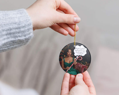Person holding a circular ornament with a photo of a woman and text, against a neutral background.