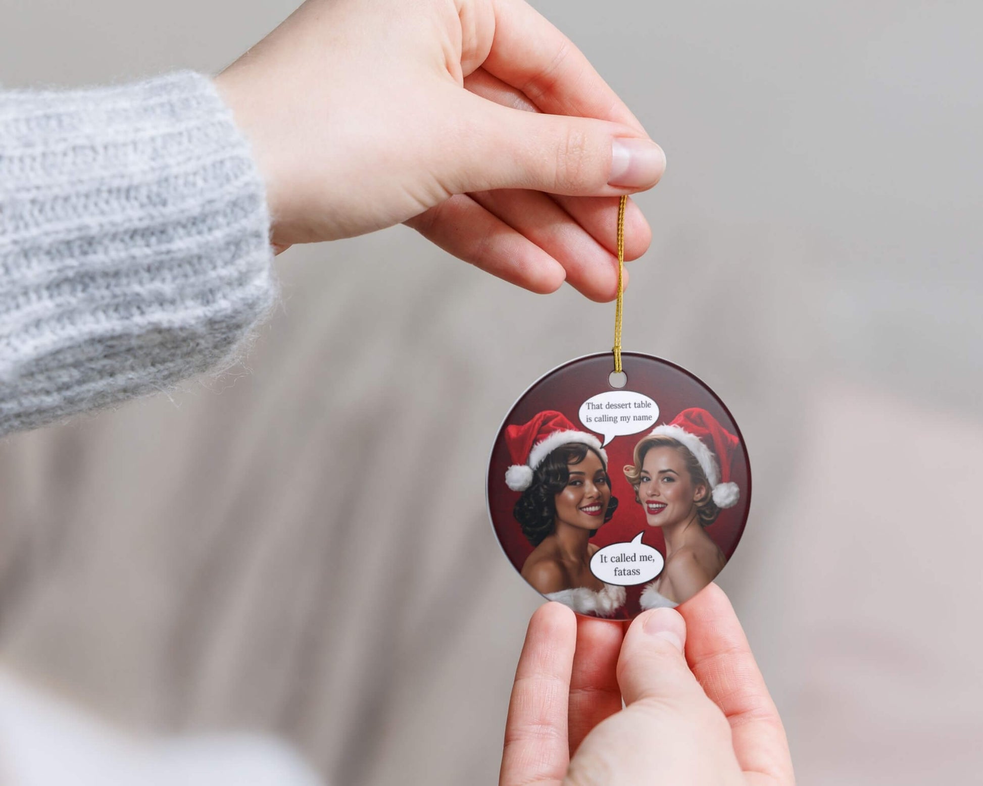 Person holding a Christmas ornament with two women in Santa hats and text.