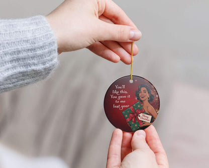 Hand holding a decorative ornament with text and graphics on a neutral background