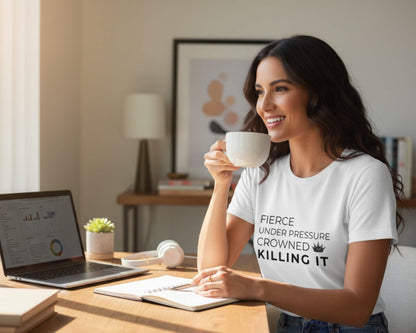 Woman in a home office holding a mug and wearing a t-shirt with a motivational quote.