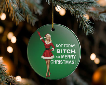 Christmas ornament with a graphic of a woman in a Santa outfit and text, hanging on a tree.