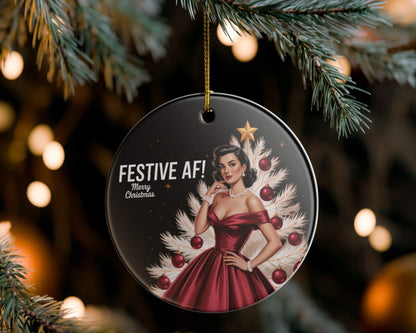 Christmas ornament with a woman in a red dress and festive tree design, hanging on a tree.