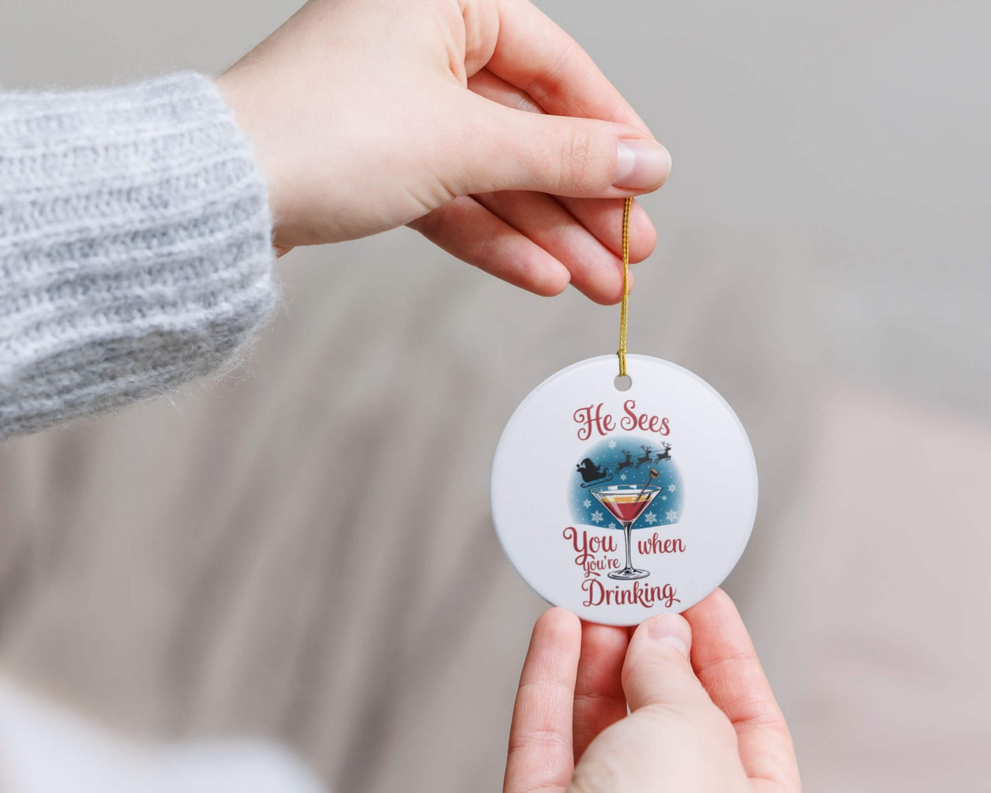 Round decorative ornament with humorous text held by a person against a neutral background