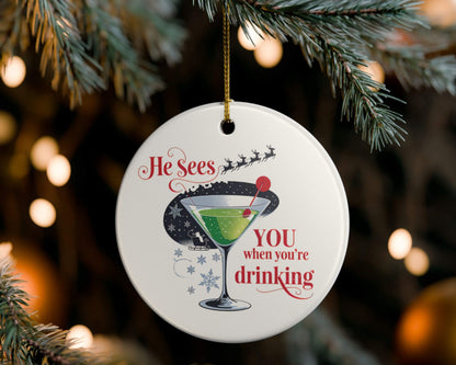 Christmas ornament with a cocktail graphic and humorous text, hanging on a tree.